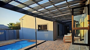 A covered outdoor area with a swimming pool, a patio with brick flooring, and a glass door leading to an interior space. - Room-king Deluxe Apartment-style Room (Cape Town)