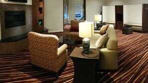 Een hotelkamer met een open haard, een bank, een stoel, een televisie en een lamp.
