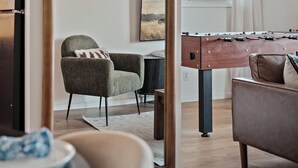 Una sala de estar moderna con una mesa de fútbol, un sofá, una silla y una mesa de comedor.