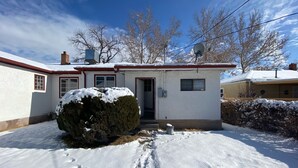 A two-story house with a snow-covered front yard, a satellite dish, and a chimney. - Charming basement separate entrance  2-bedroom house with AC in welcoming Pueblo (Pueblo)