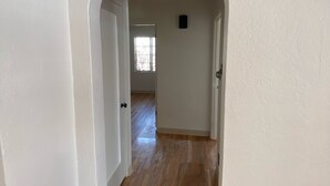 A hallway with white walls and wooden flooring, leading to a room with a window. - Charming basement separate entrance  2-bedroom house with AC in welcoming Pueblo (Pueblo)