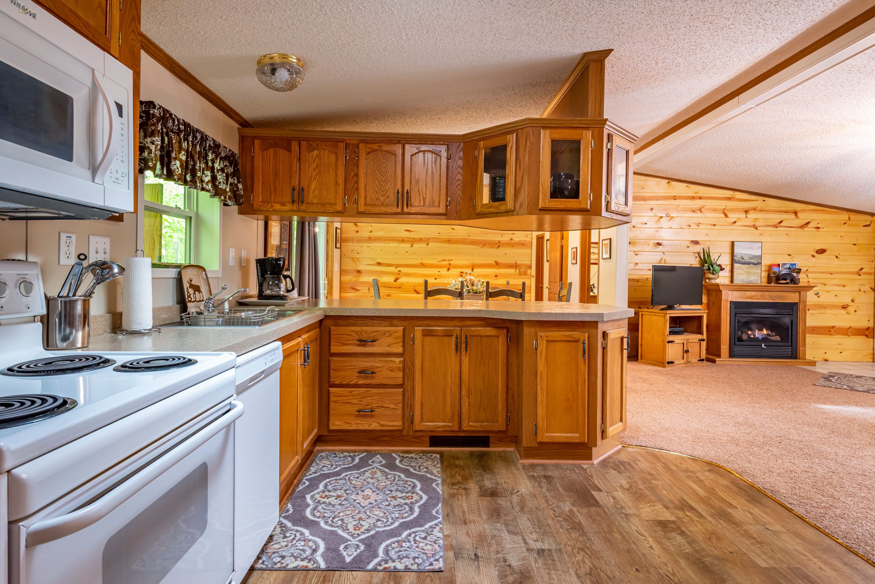 A kitchen with wooden cabinets, a microwave, stove, and a fireplace.
