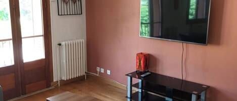 Een woonkamer met een bank, een salontafel, een tv op een meubel en een radiator.