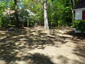 A forested area with a large tree, a white building with red shutters, and a yellow pole. - Comfortable 1-bedroom in enchanting Charlotte (Charlotte)