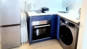 A compact kitchen with a built-in oven, a washing machine, and a sink. - Apartment close to the beach, restaurant and beautiful sunsets. (Viña del Mar)
