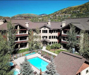 Ein Resort mit mehreren Gebäuden, einem Swimmingpool und einer Bergkulisse.