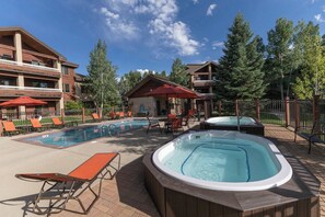 A hotel pool area with lounge chairs, a hot tub, and a covered seating area. - Aspen Oasis | 2BR, Private Hot Tub, Resort Pools (Steamboat Springs)