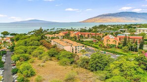 A coastal resort with multiple buildings, a parking area, and a view of the sea and a mountain. - Double Master 2BR Villa | Pacific Shores | Kihei (Kihei)