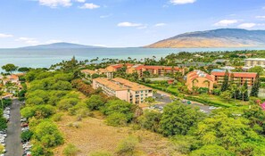 Ein Resort mit mehreren Gebäuden, einem Parkplatz und Blick auf das Meer und die Berge.