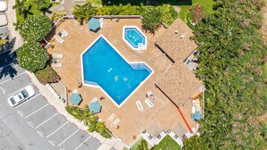 An aerial view of a swimming pool area with multiple lounge chairs and a smaller pool. - Double Master 2BR Villa | Pacific Shores | Kihei (Kihei)