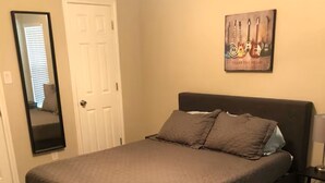 Ein Schlafzimmer mit einem Bett, einer Tür, einem Spiegel und einem Wandbild.
