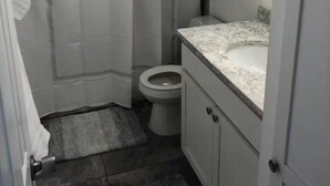 Ein Badezimmer mit Duschvorhang, Toilette und Marmorplatte.