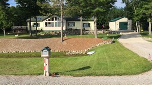 A residential property with a well-maintained lawn, a mailbox, and a driveway leading to a house with a green roof. - Enjoy a bed & breakfast with view of Lake Huron, sunrises and eagles! (Ocqueoc)