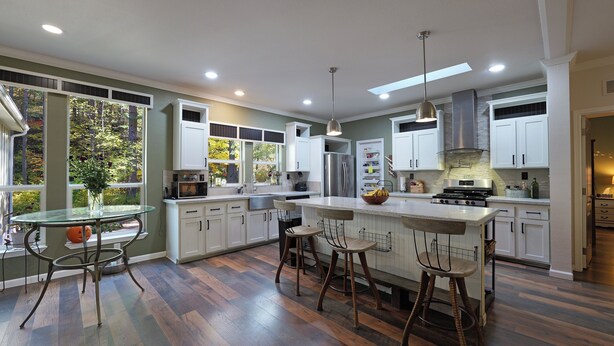 A modern kitchen with white cabinets, a stainless steel refrigerator, and a large island with bar stools.