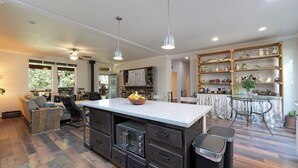 A modern kitchen with a central island, built-in oven, and a dining area with a glass table.