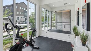 Een moderne sportschool met grote ramen, trainingsfietsen en uitzicht op buiten.