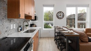 Een moderne keuken met een centraal eiland, houten kastjes en een groot raam.