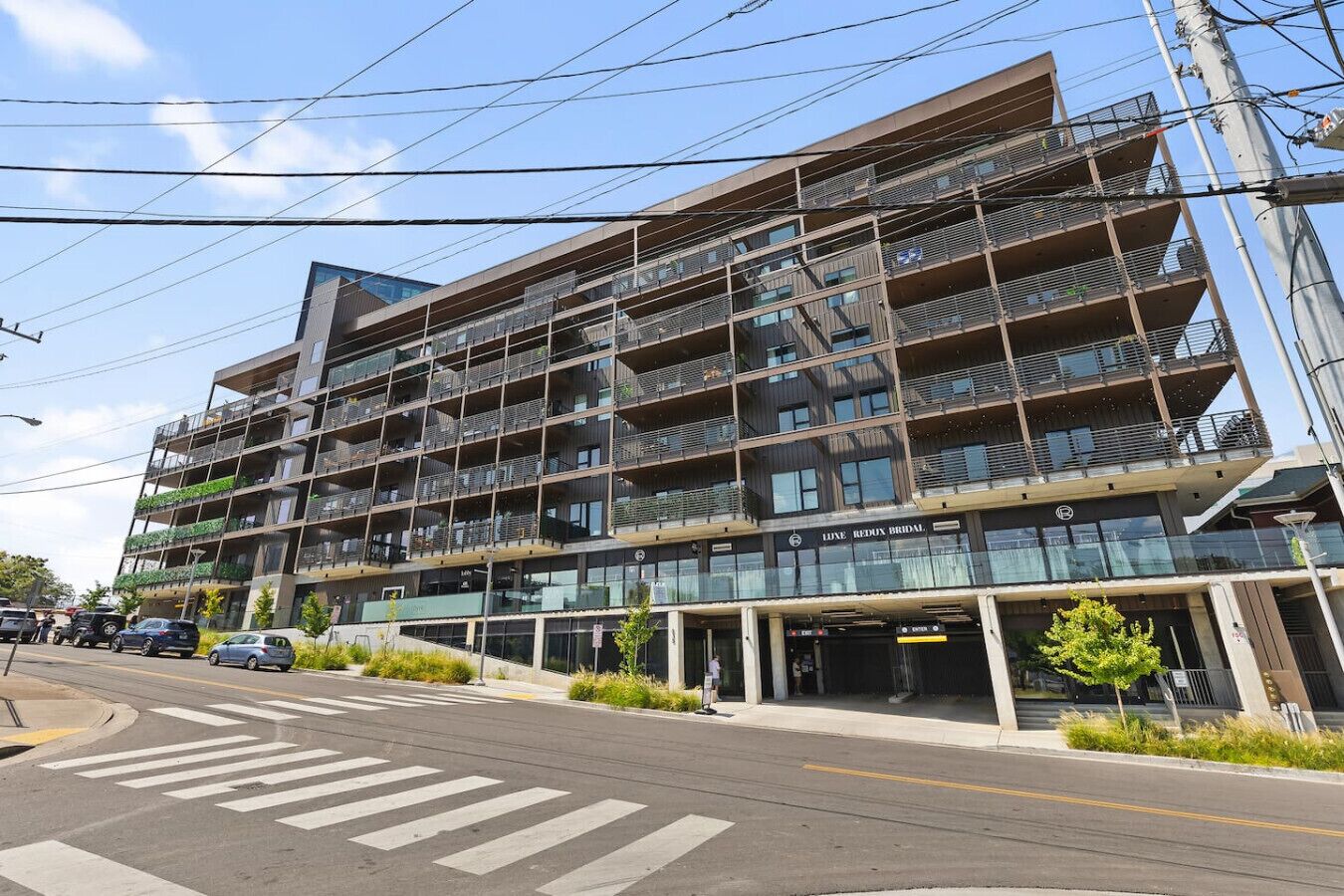 A multi-story building with balconies, a storefront, and a crosswalk.