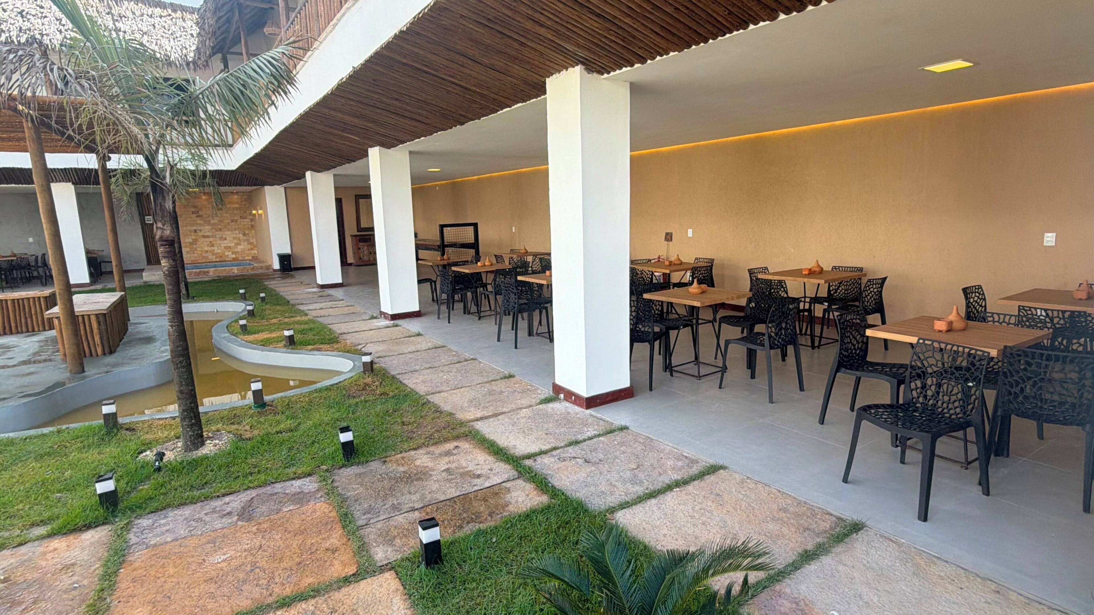 An outdoor seating area with tables and chairs, a curved pathway, and a small water feature.
