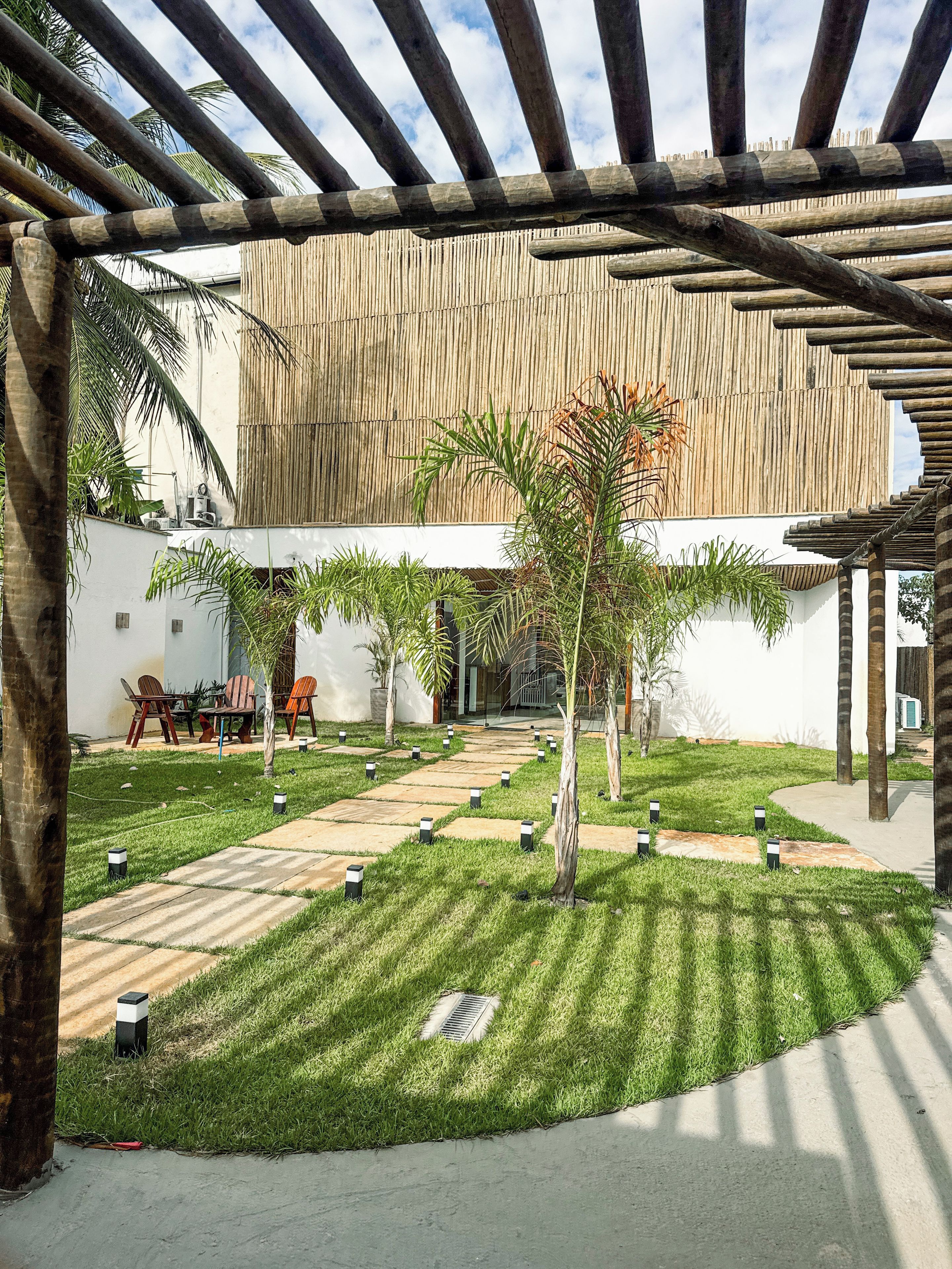 A courtyard with a pergola, seating area, and a bamboo wall.
