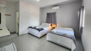 Ein Hotelzimmer mit zwei Betten, einem Schreibtisch und einer kleinen Küchenzeile.