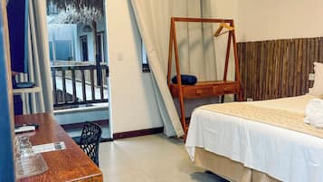 Habitación de hotel con cama, escritorio, silla, sillón colgante y vista a un balcón.