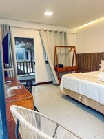 Habitación de hotel con cama, escritorio, silla, sillón colgante y vista a un balcón.