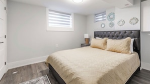 A bedroom with a bed, a nightstand, a wall-mounted lamp, and decorative wall plates. - Luxury Suite by Kensington Market Downtown Toronto (Toronto)