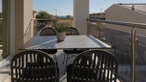 A balcony with a table and chairs, a potted plant, and a clear view of the surrounding area. - Bianco Mare Studios-Apartments (Kalyves Polygyrou)