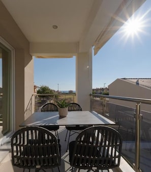 A balcony with a table and chairs, a potted plant, and a clear view of the surrounding area. - Bianco Mare Studios-Apartments (Kalyves Polygyrou)