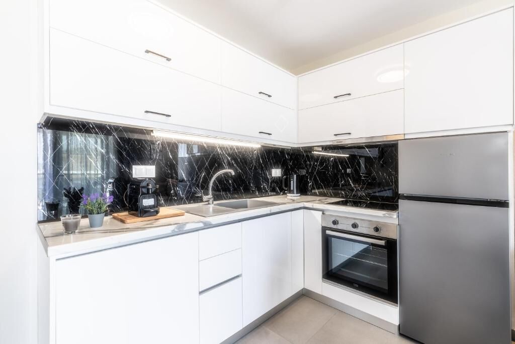 Een moderne keuken met witte kastjes, een zwart aanrecht en roestvrijstalen apparatuur.