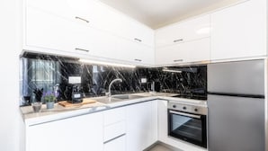 A modern kitchen with white cabinets, a black countertop, and stainless steel appliances. - Bianco Mare Studios-Apartments (Kalyves Polygyrou)