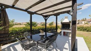 Une terrasse extérieure avec une table et des chaises, un barbecue et une vue sur les environs.