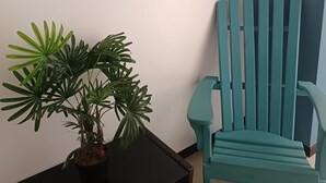 Een teal kleurstol, een potplant en wanddecoraties in een kamer met een betegelde vloer.
