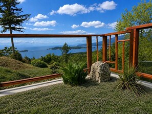 A wooden deck with a view of the sea and hills.