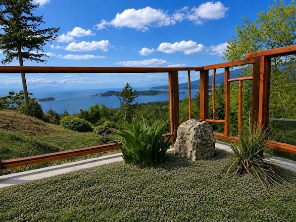 A wooden deck with a view of the sea and hills.