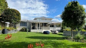 A house with a covered porch, a lawn, and a tree. - Spacious 4 BRM home with spa and large garden (Taupō)