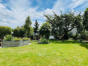 A well-maintained garden with a wooden fence, a bench, and various plants. - Spacious 4 BRM home with spa and large garden (Taupō)