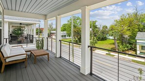 A covered porch with a white railing, a wooden bench, and a white sofa. - Luxurious Newer Home - Prime Location in Downtown Pensacola - Outdoor Kitchen - Private Weight Room (Pensacola)