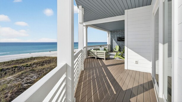 Une véranda donnant sur la plage, avec des balustrades blanches et une chaise verte.