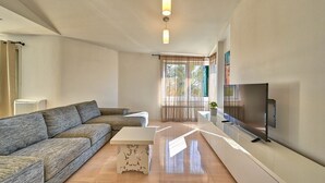 A modern living room with a sofa, a coffee table, a TV, and a window with curtains. - Dionis apartment - 3 bedroom apartment with shared pool in a quiet neighborhood (Zadar)