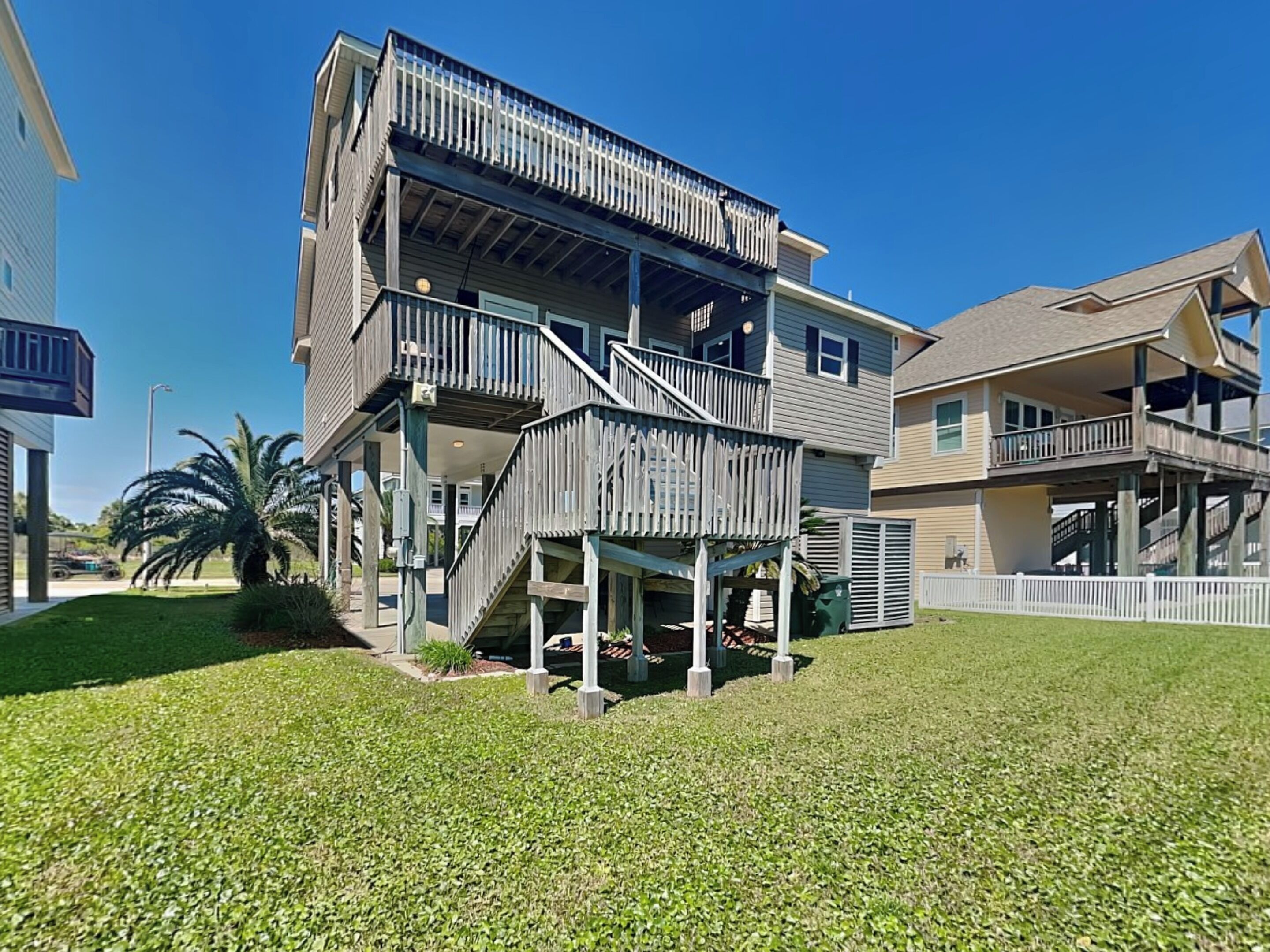 A multi-story residential building with a balcony, a covered porch, and a well-maintained lawn.