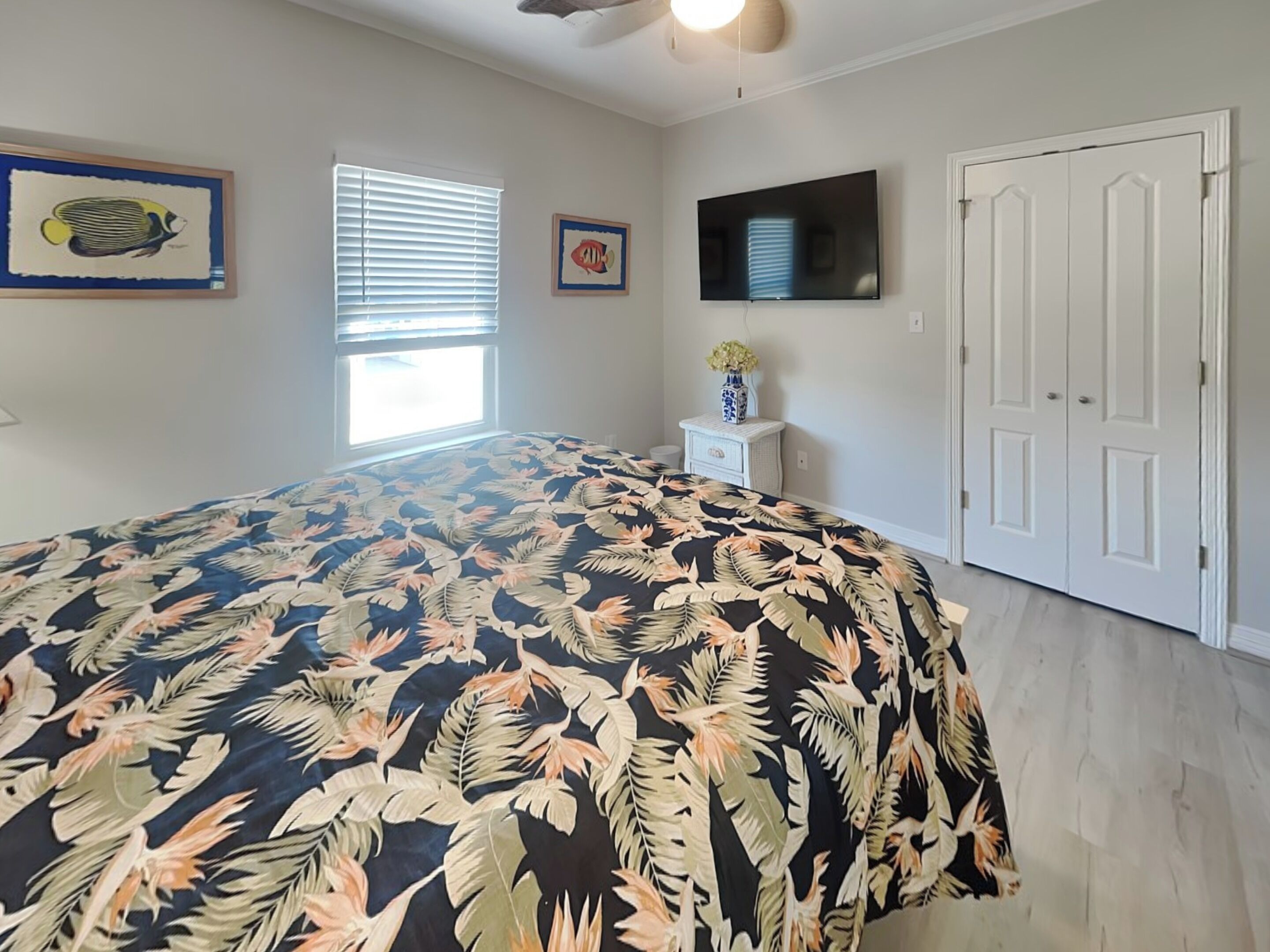 A bedroom with a bed, a TV, a window, and a door.