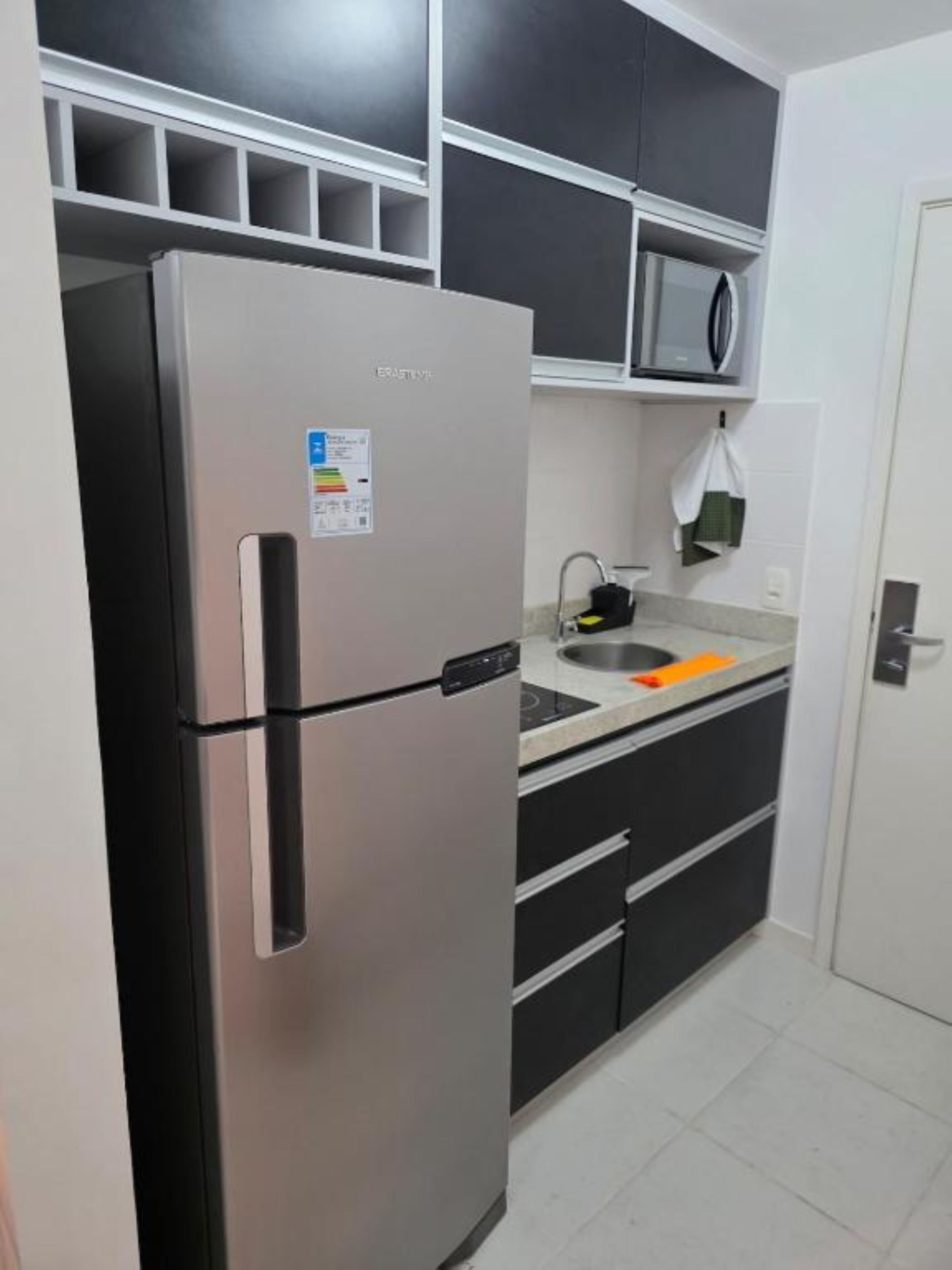 A kitchen with a stainless steel refrigerator, a microwave, and a sink.