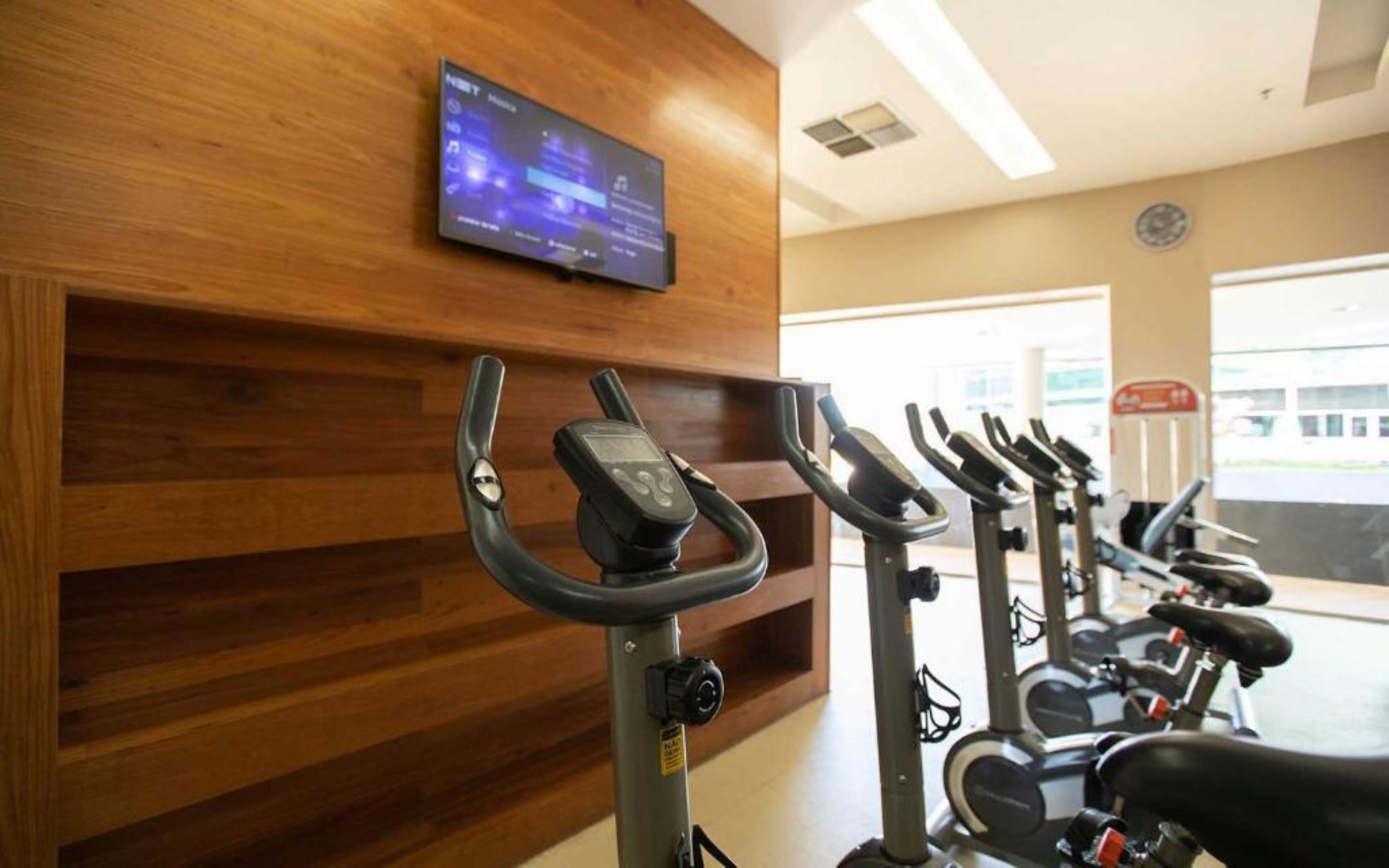 A gym with exercise bikes and a television mounted on the wall.