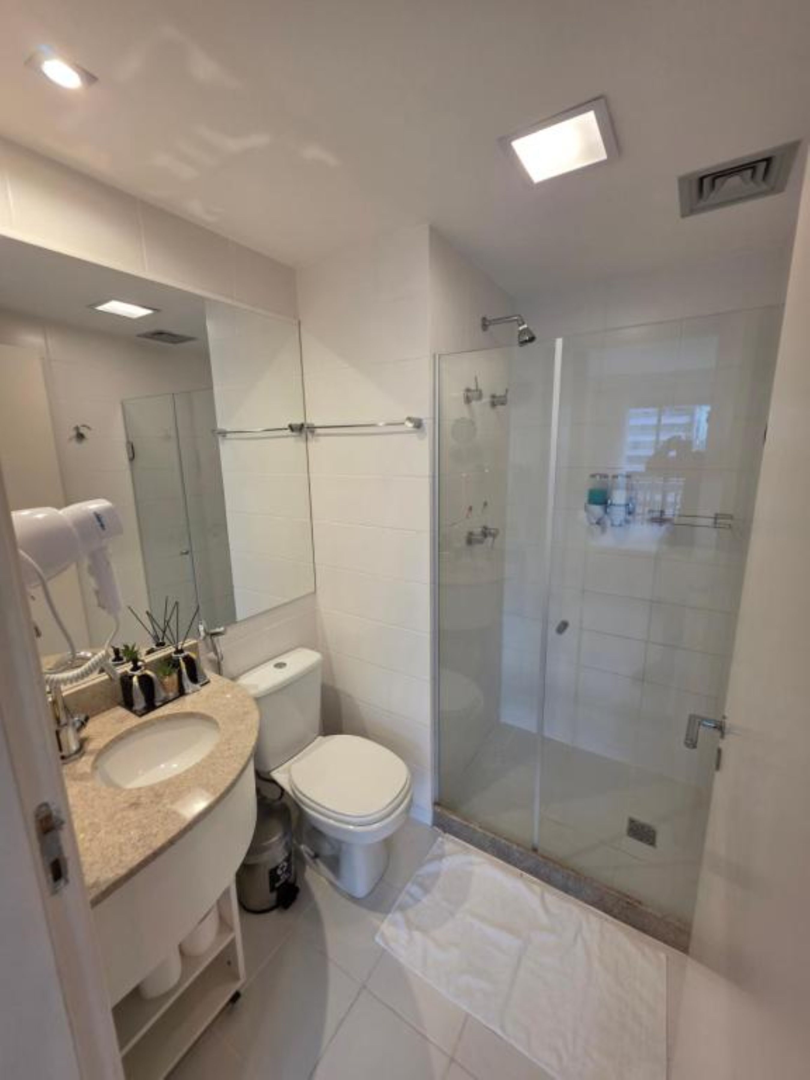A modern bathroom with a glass shower enclosure, a white toilet, and a vanity with a sink.