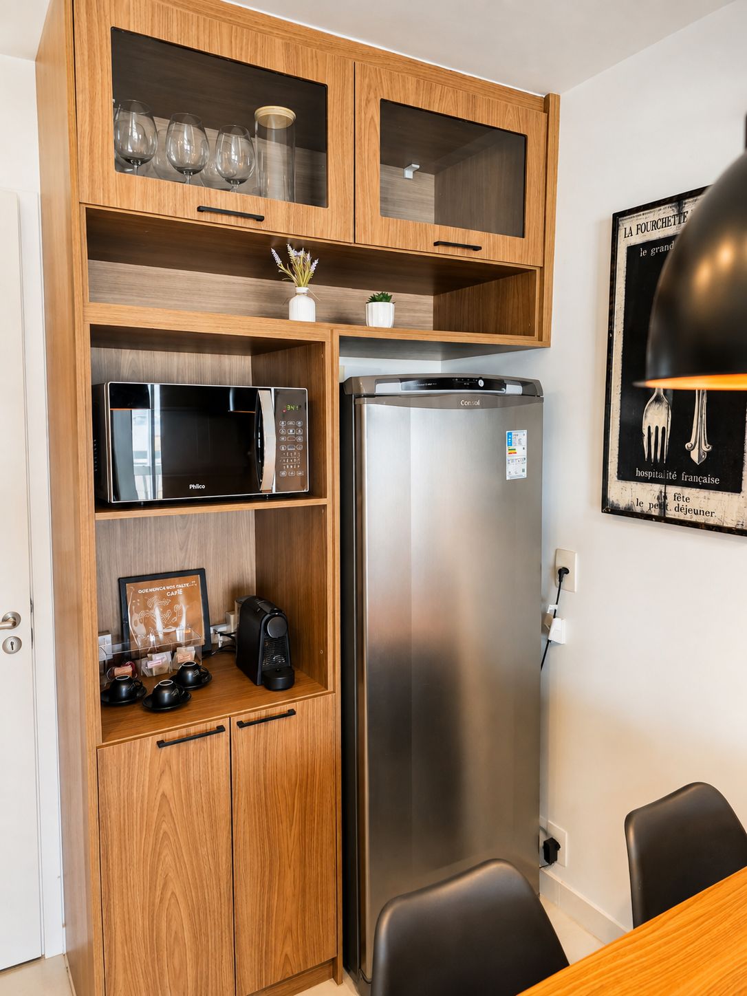 A compact kitchenette with a microwave, refrigerator, and wooden cabinetry.