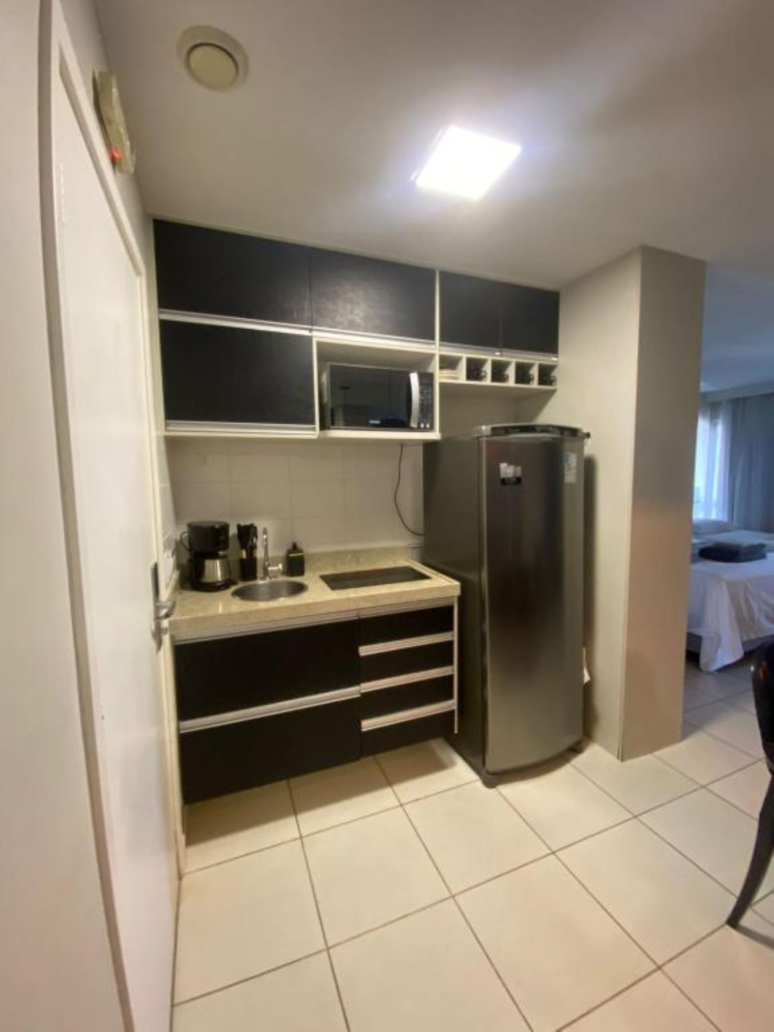 Una cocina compacta equipada con microondas, refrigerador y cafetera.