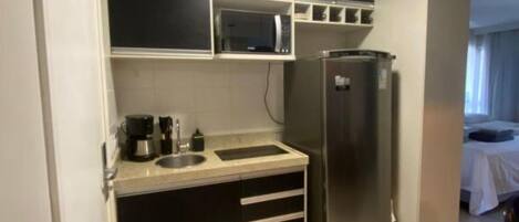 Una cocina compacta equipada con microondas, refrigerador y cafetera.