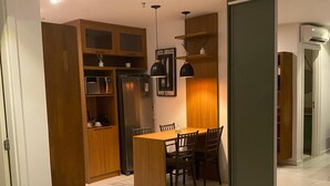A modern bedroom with a large bed, a small dining area, and a kitchen with wooden cabinets. - Flats Premium com vista Incrível no hotel Vision (Brasília)